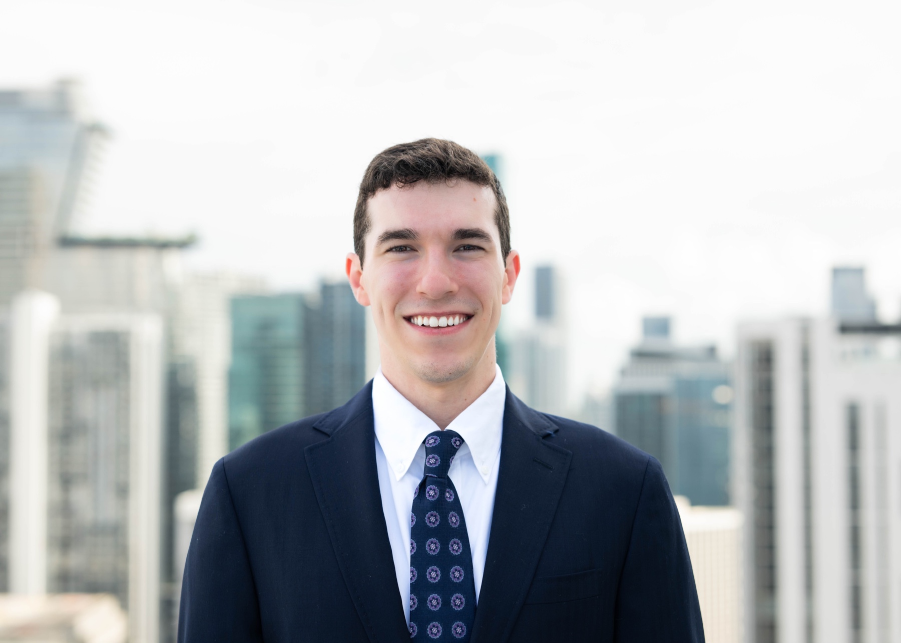 Joe Ferber smiling in a navy suit with the Chicago skyline behind him